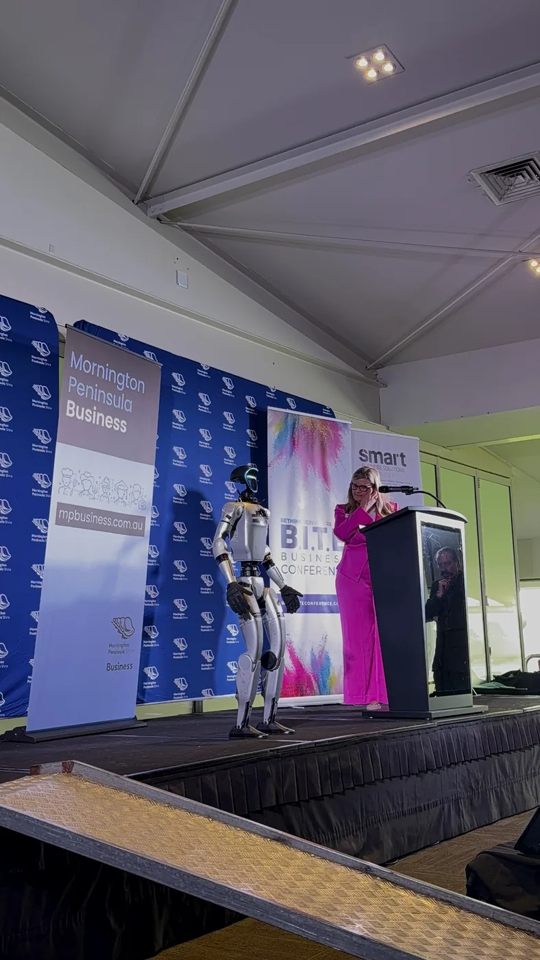 Rocco on stage beside a presenter at the B.I.T.E Business Conference, Mornington Racecourse