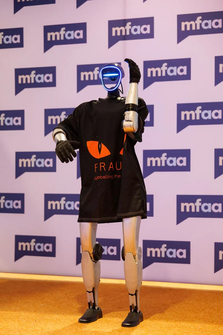 Rocco humanoid robot in a FraudX t-shirt at the MFAA National Conference media wall