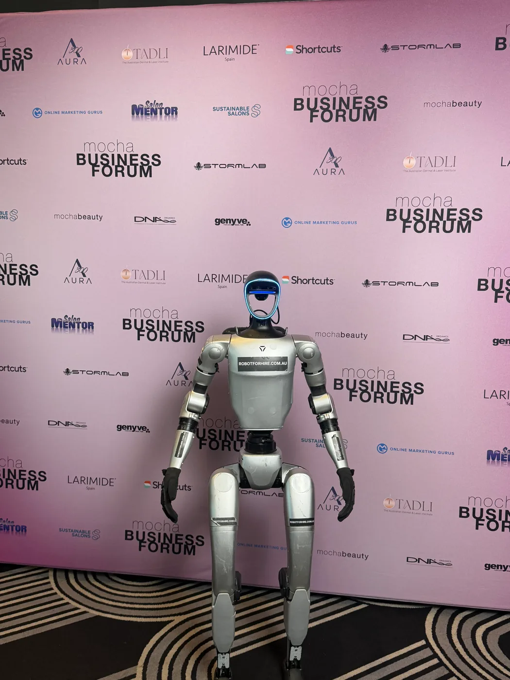 Rocco in front of the Mocha Business Forum sponsor wall