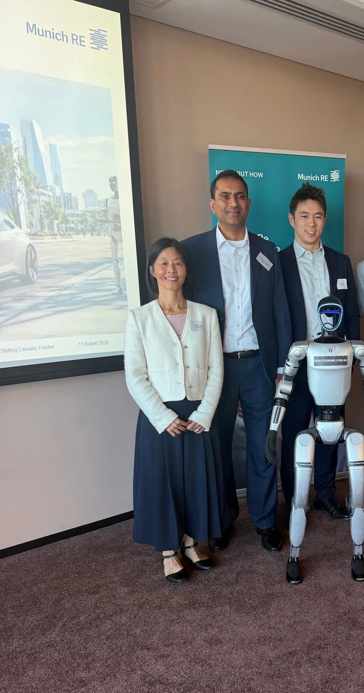 Rocco the humanoid robot with Munich Re presenters in front of Munich Re signage at the Knowledge Brew session