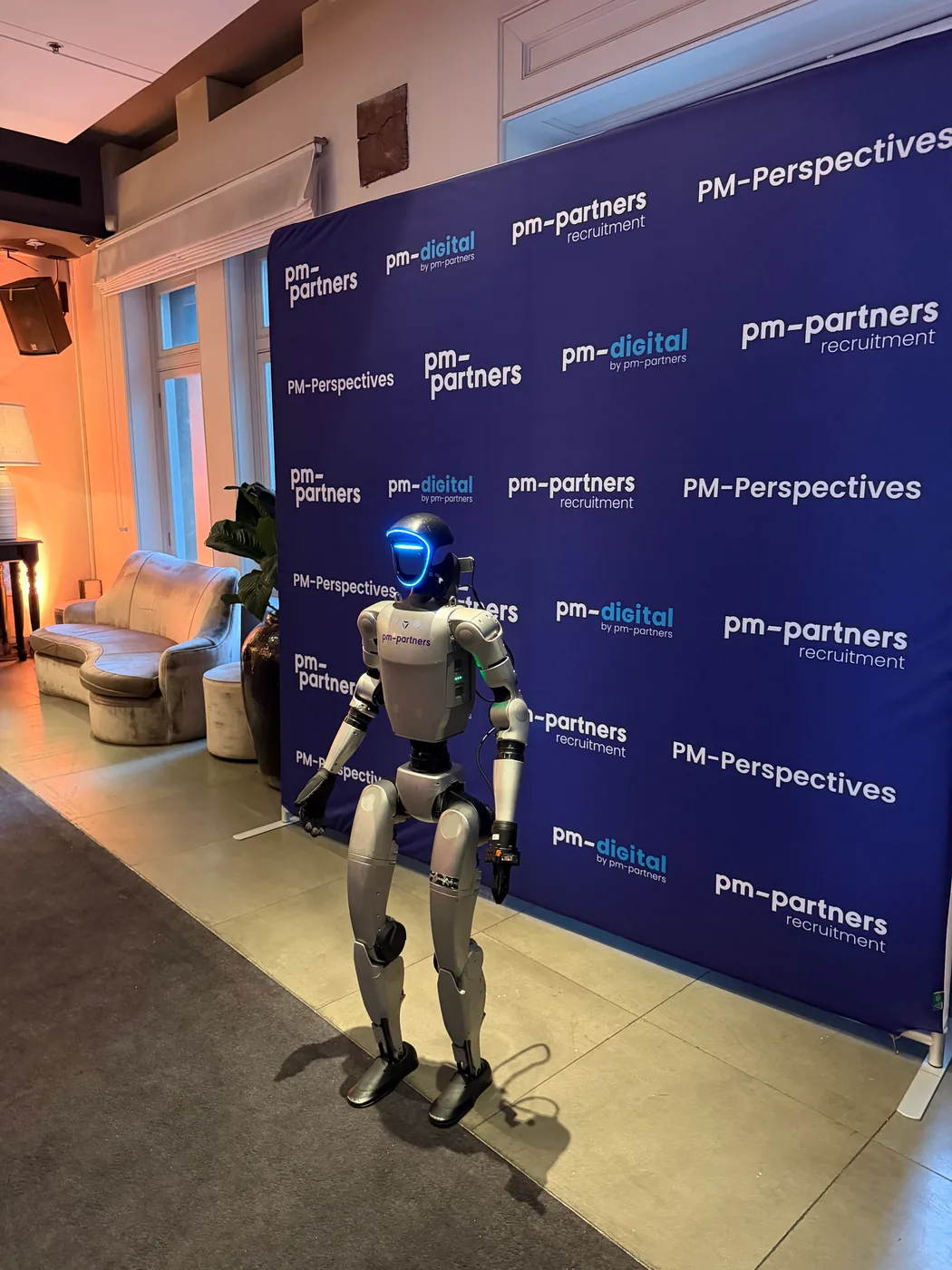 Rocco with a pm-partners sticker in front of the PM-Perspectives media wall