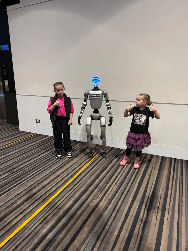 Rocco humanoid robot posing with two young guests at an event